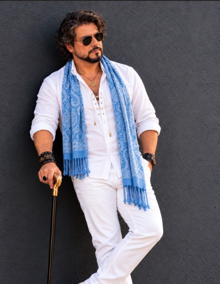 Composição masculina com camisa clara, lenço e acessórios diante de uma parede escura